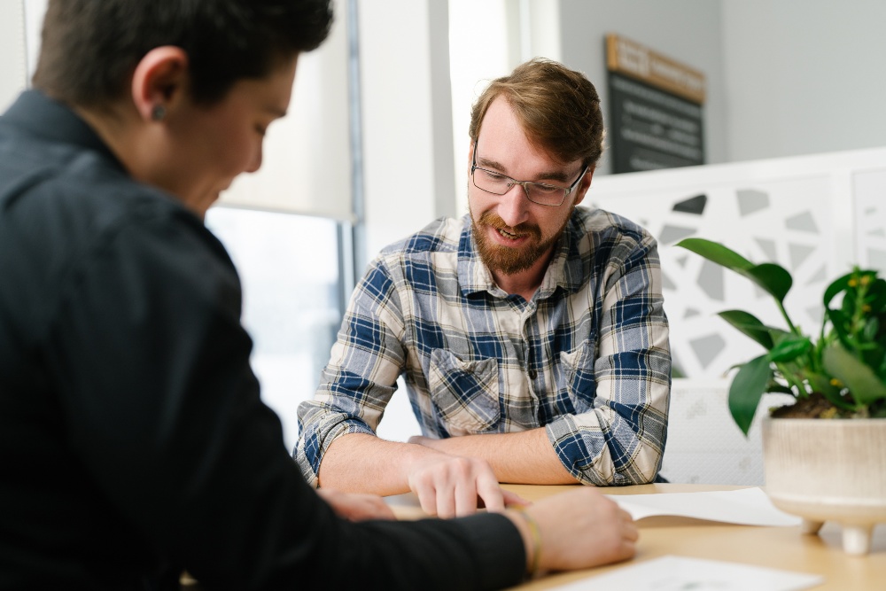 Man and CU1 representative discussing finances at a desk in a CU1 branch