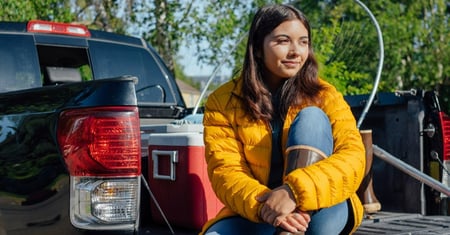 A woman sitting on the bed of her truck