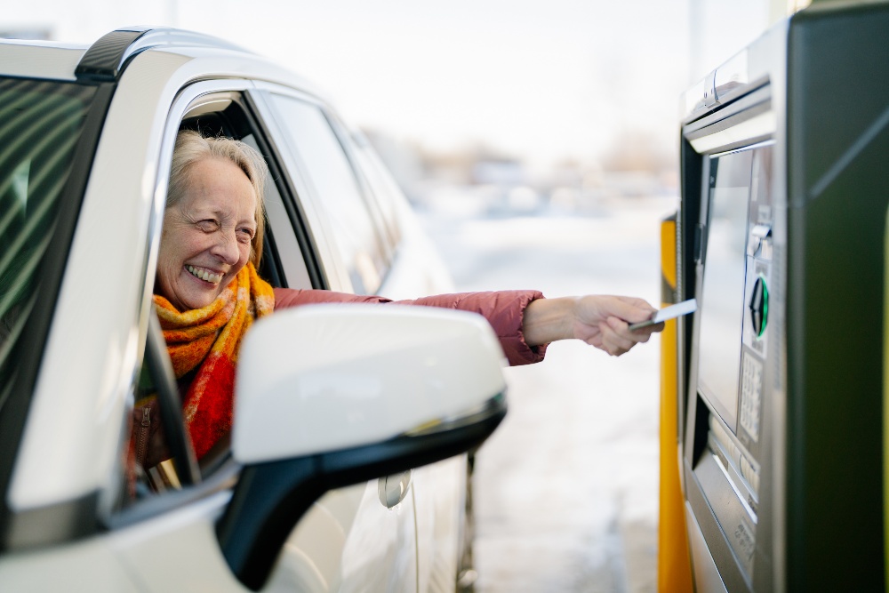 Woman in her car with her hand out the window and inserting a card into an ITM