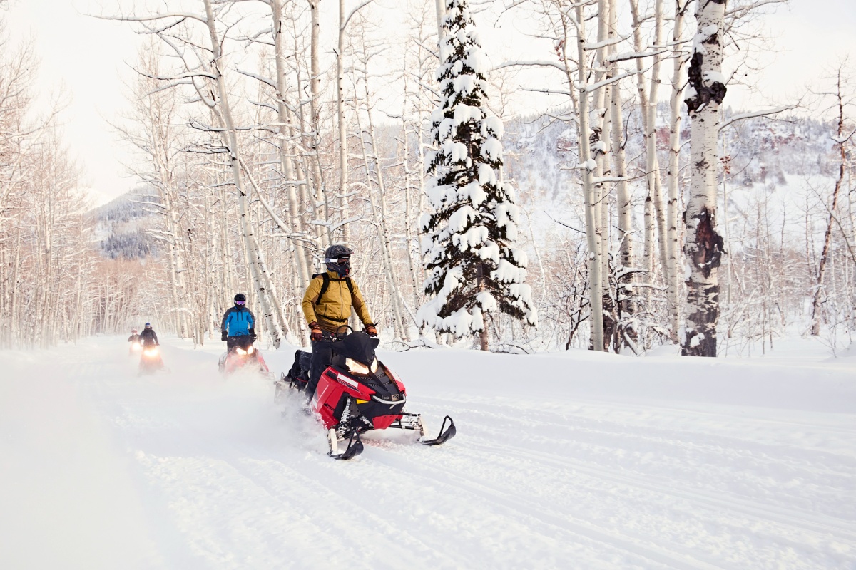 3 snowmachiners riding through the pass on an Alaskan trail.